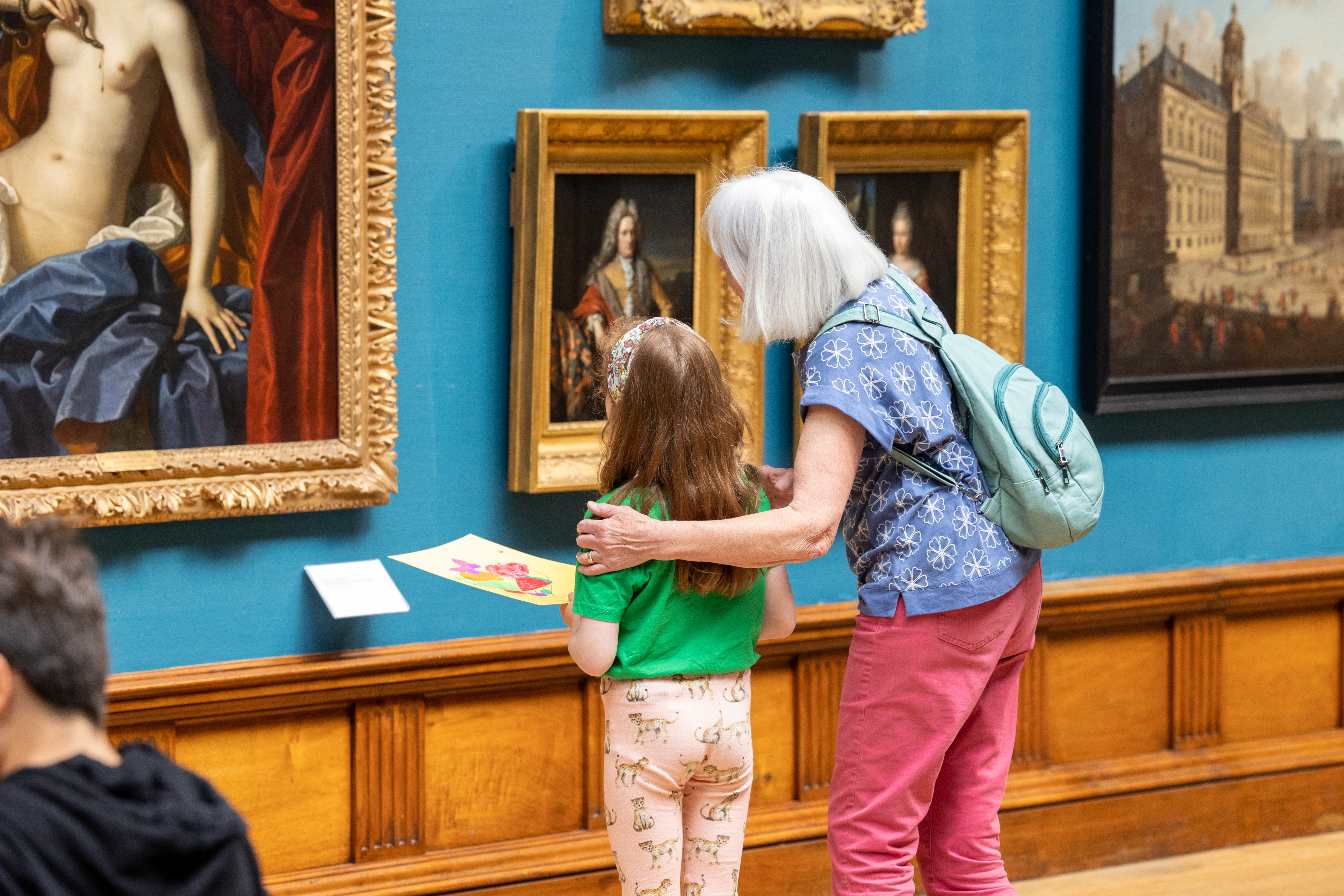 An adult and child looking at paintings in the Upper Gallery