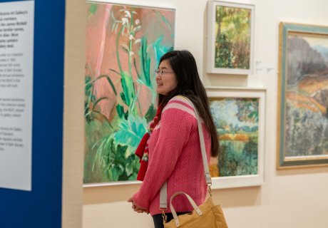 Image: A visitor looking at artworks in the New English Art Club exhibition