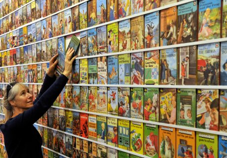 Image: Helen Day, Ladybird expert and enthusiast, standing beside a wall of colourful Ladybird books