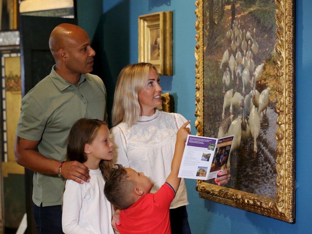 Image: A family looking at a Discovery Card flyer in the Upper Gallery