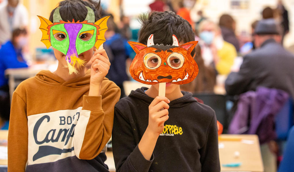 Image: Children holding up masks they made at a craft activity