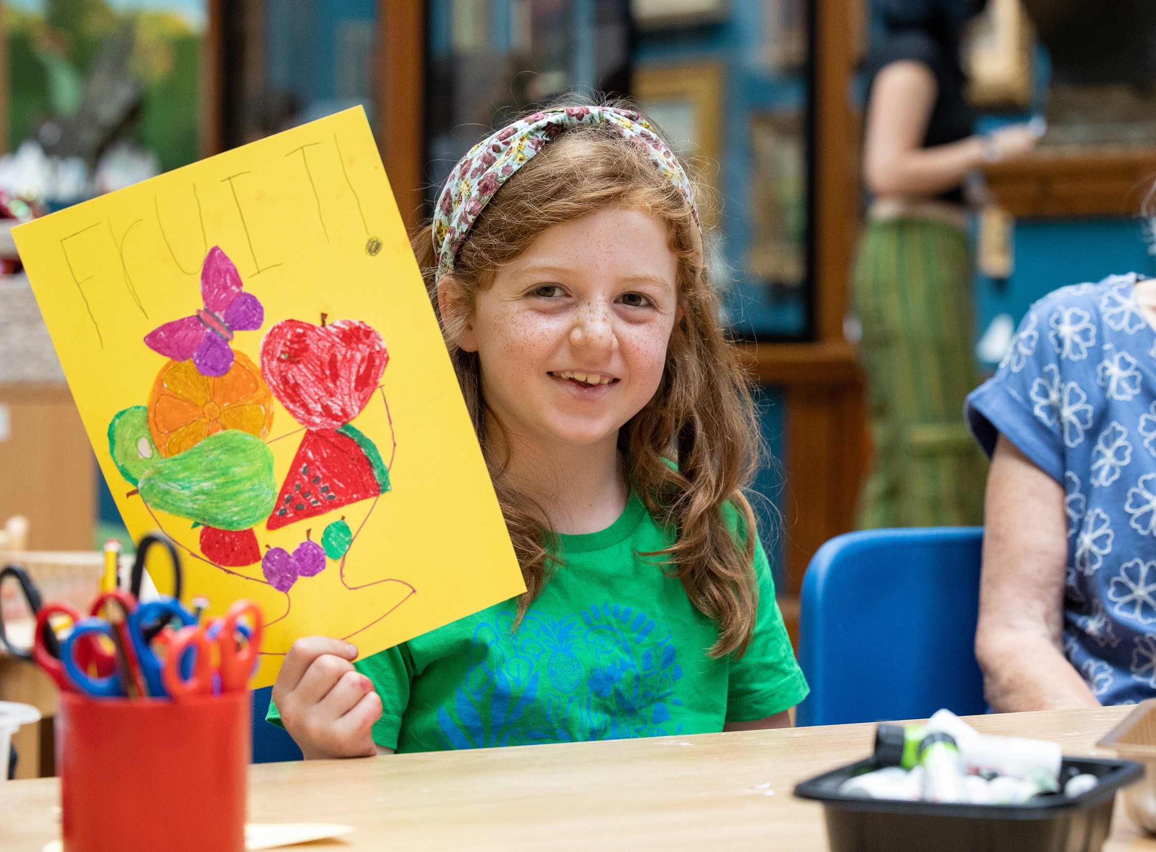 A child holding up a piece of artwork that she has made.