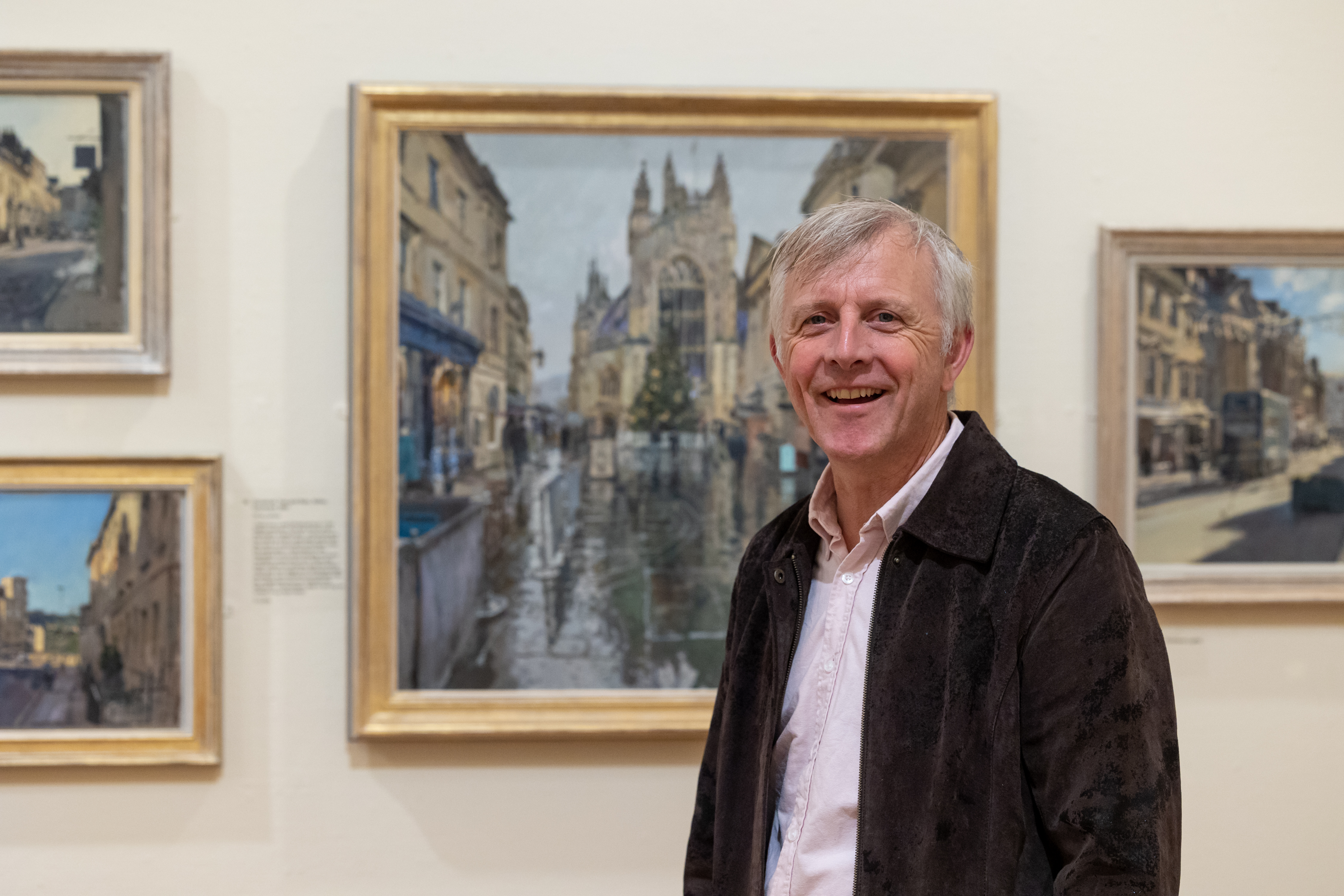 Image: Artist Peter Brown standing in front of some of his paintings