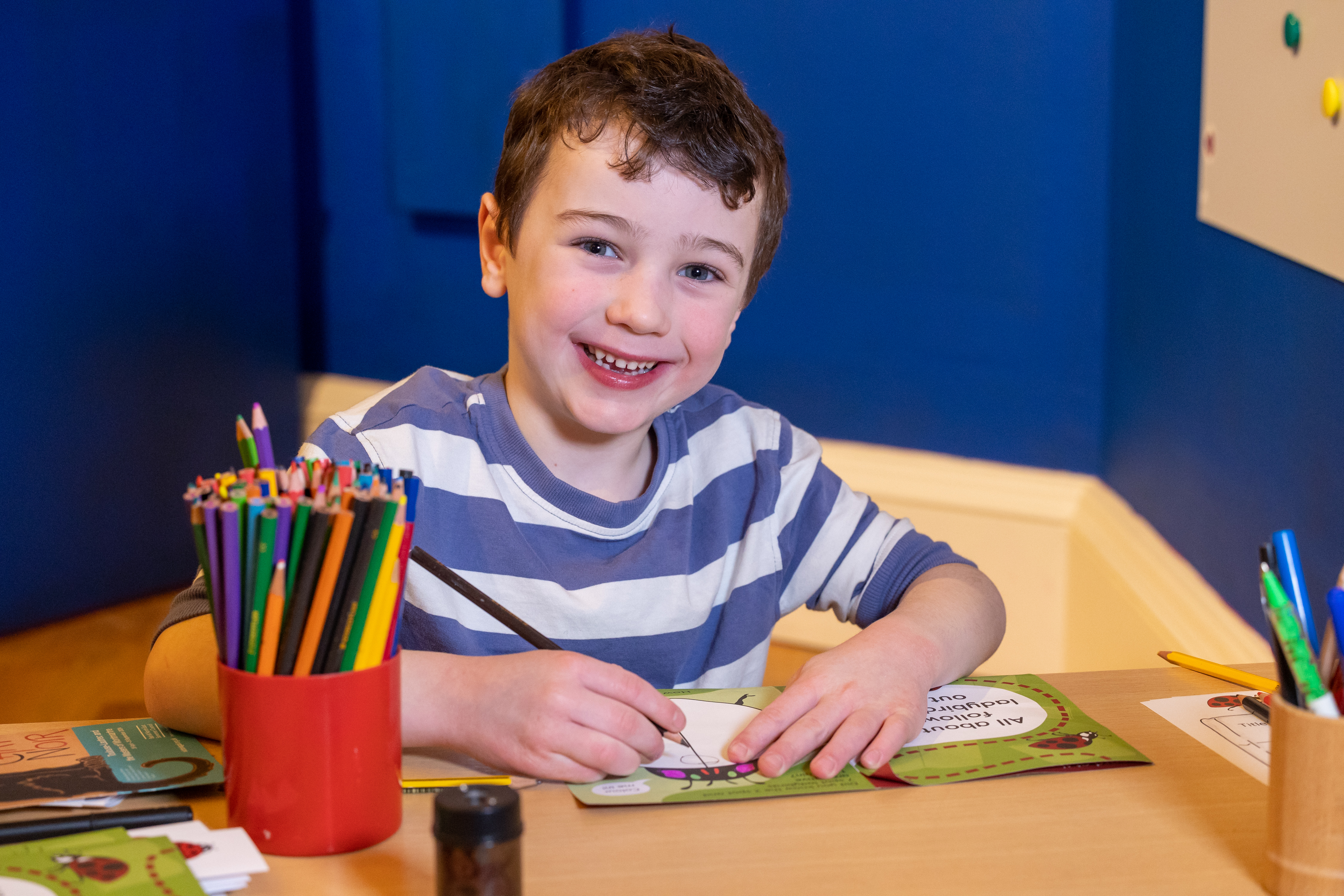 A boy drawing in a book with pencils